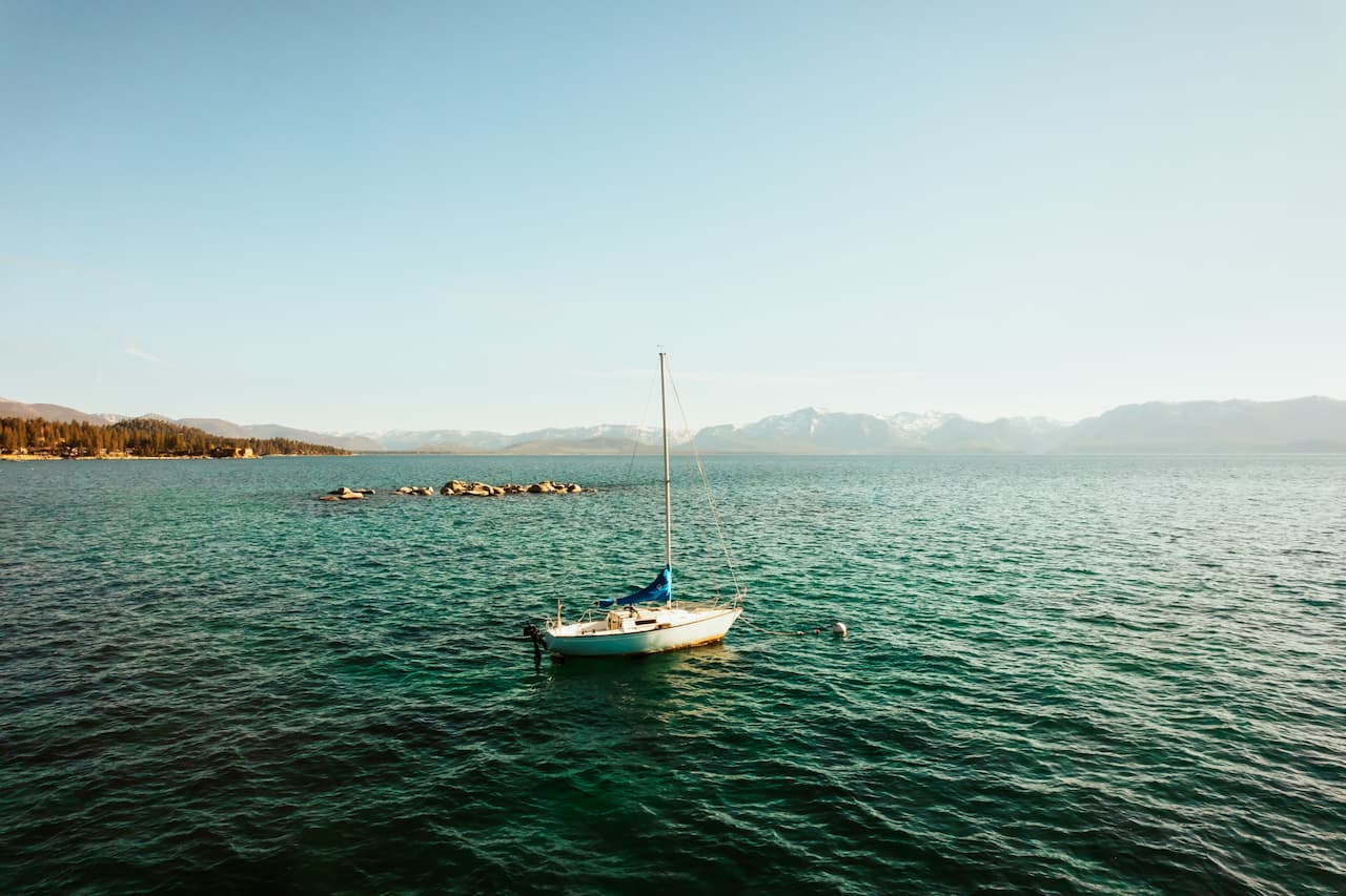 Lake Tahoe water with a sailboat and mountain shoreline