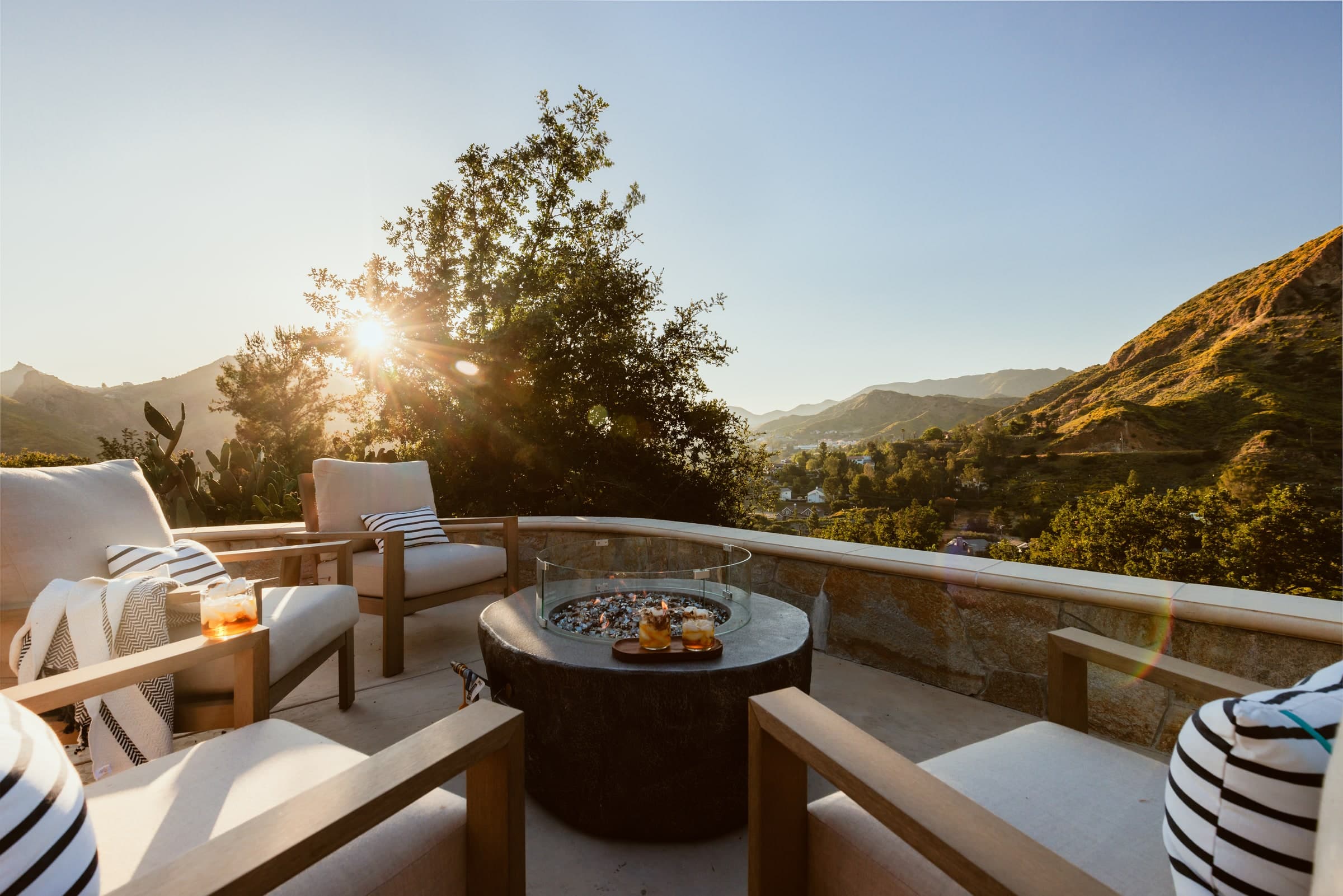 Sunlit terrace with cushioned seating around a round fire pit