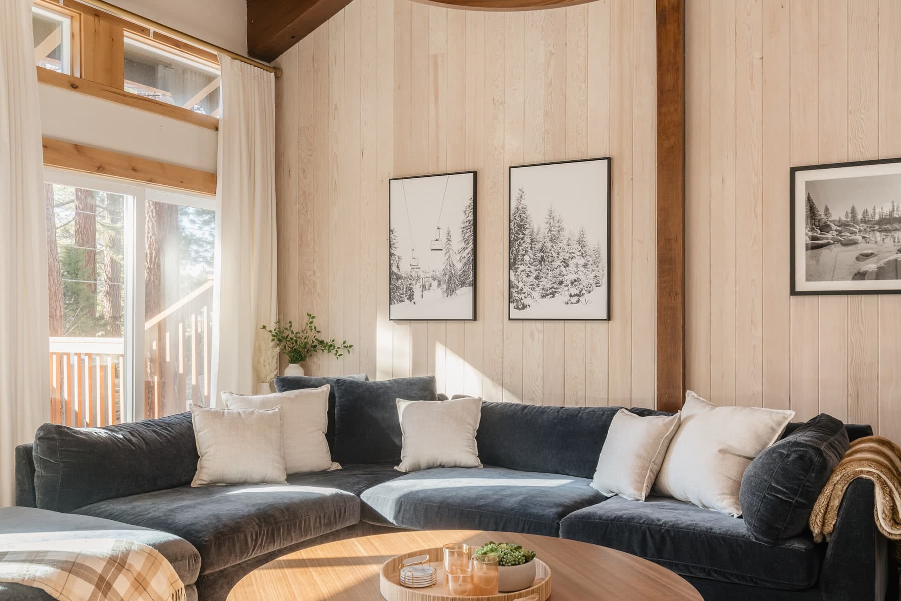 Dark sectional sofa in a wood-paneled living room with framed landscape prints