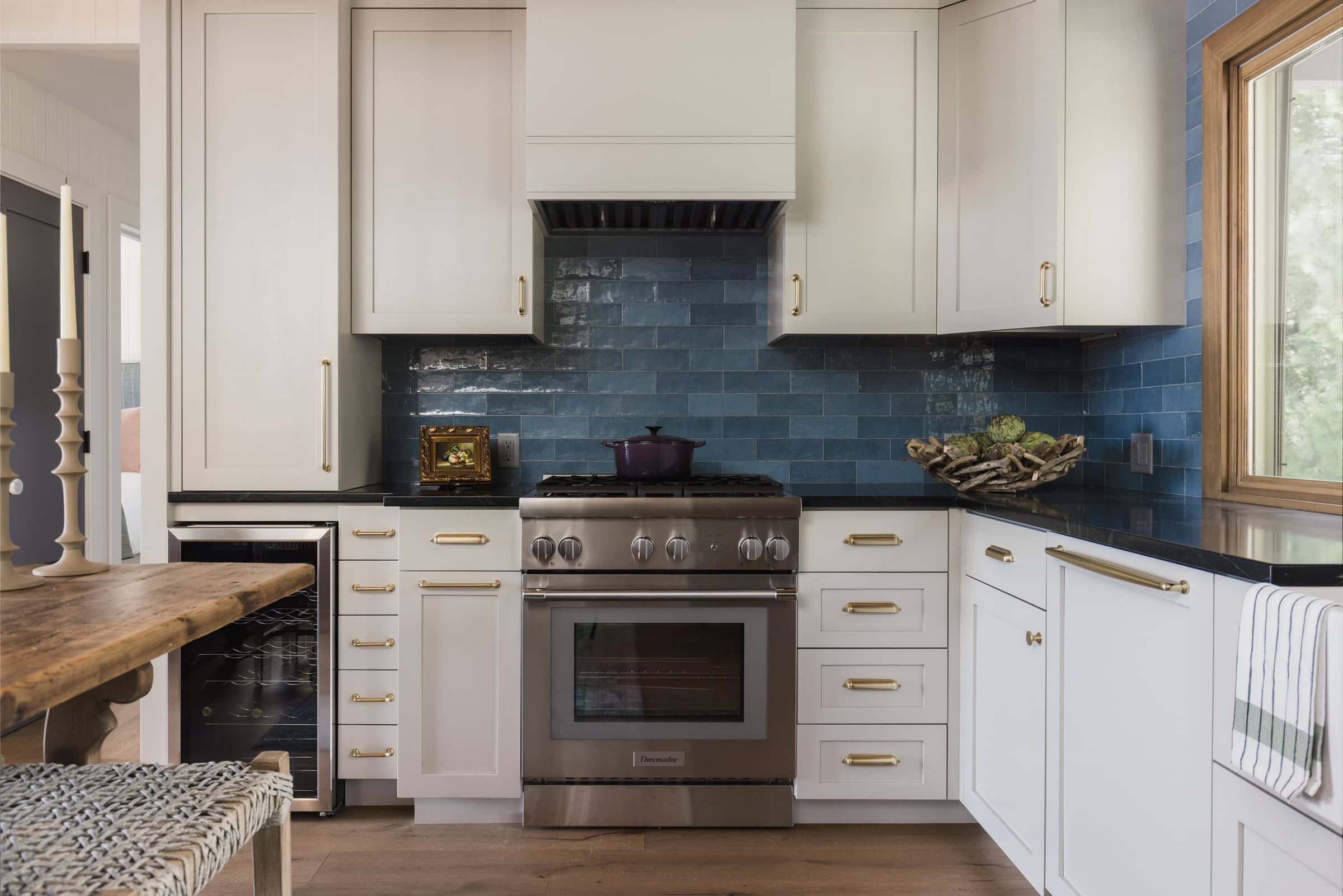 White kitchen with blue tile backsplash, stainless range, and dark stone counters